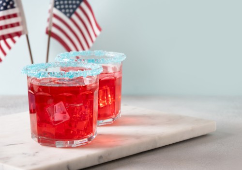 Two red drinks with sugared rims on a marble surface, accompanied by American flags in the background.