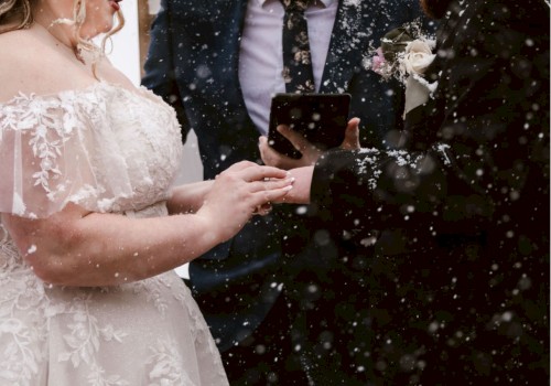 A couple exchanging rings during an outdoor wedding ceremony in the snow, accompanied by an officiant holding a book.